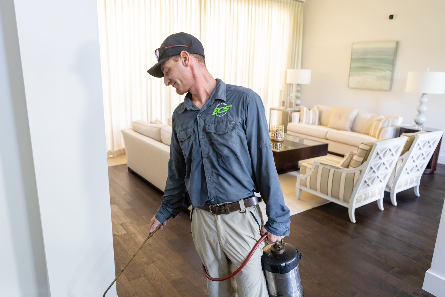 exterminator spraying living room with indoor bug treatment